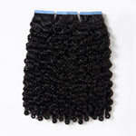 Burmese Curly Tape In Hair Extensions by UrbanChichair, double drawn black human hair with defined curls and blue tape tabs on a clean white background