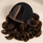 Close-up of deep brown human hair with warm brown highlights and soft loose body waves.
