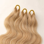 Close-up of three pre-looped #27/#613 blonde body wave human crochet hair strands for easier installation