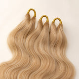 Close-up of three pre-looped #27/#613 blonde body wave human crochet hair strands for easier installation