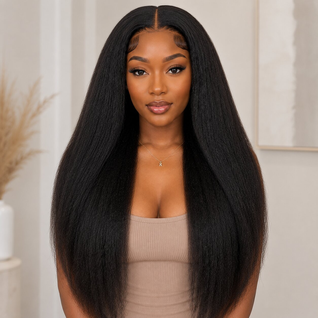 Front view of Black woman wearing long kinky straight tape in human hair extensions with natural volume and soft textured finish