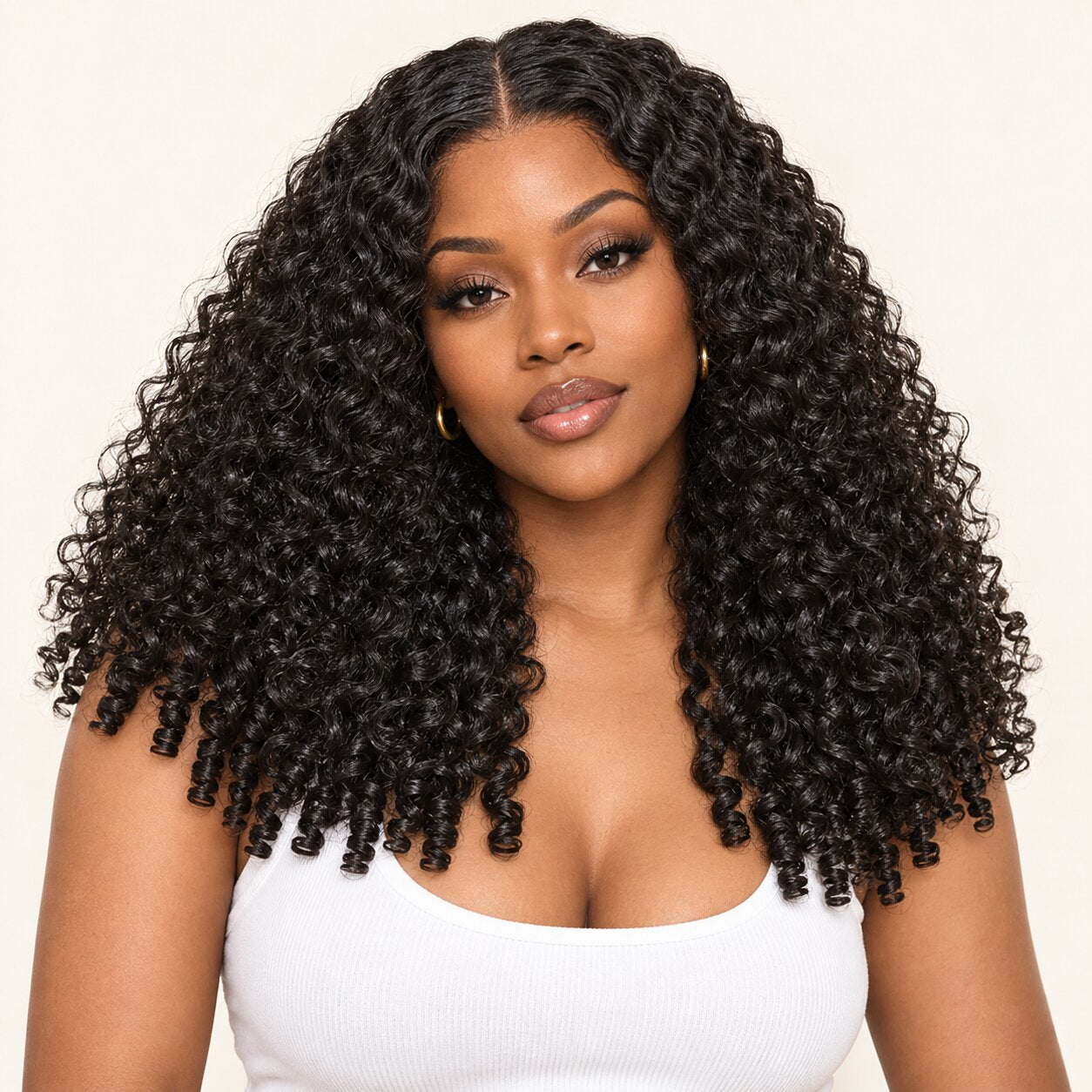 Front view of a model wearing a natural black Burmese curly wig with a middle part and defined finger-coil ends.