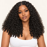 Front view of a model wearing a natural black Burmese curly wig with a middle part and defined finger-coil ends.