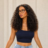 Kinky curly wig styled with the bangs pinned back, worn with glasses and a navy top.