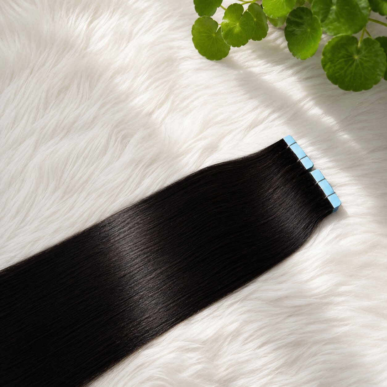 Luxury straight tape-in hair extensions displayed on soft white faux fur, featuring seamless adhesive tabs and glossy 100% human hair.