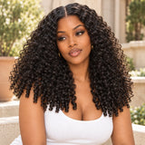 Model wearing a natural black Burmese curly wig with a middle part in a sunlit stone courtyard.