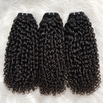 Raw Pixie Curly Bundles Double Drawn flat lay featuring three black curly human hair bundles on a soft white fur background by UrbanChichair