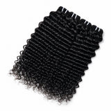 Raw water wave human hair bundles in natural black color displayed on white fur with green plant decor, showing glossy curl texture and full ends by UrbanChichair