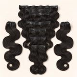 UrbanChichair Soft Body Wave Seamless Clip-in Human Hair Extensions in natural black, flat lay showing glossy body wave texture and secure clip-in wefts.